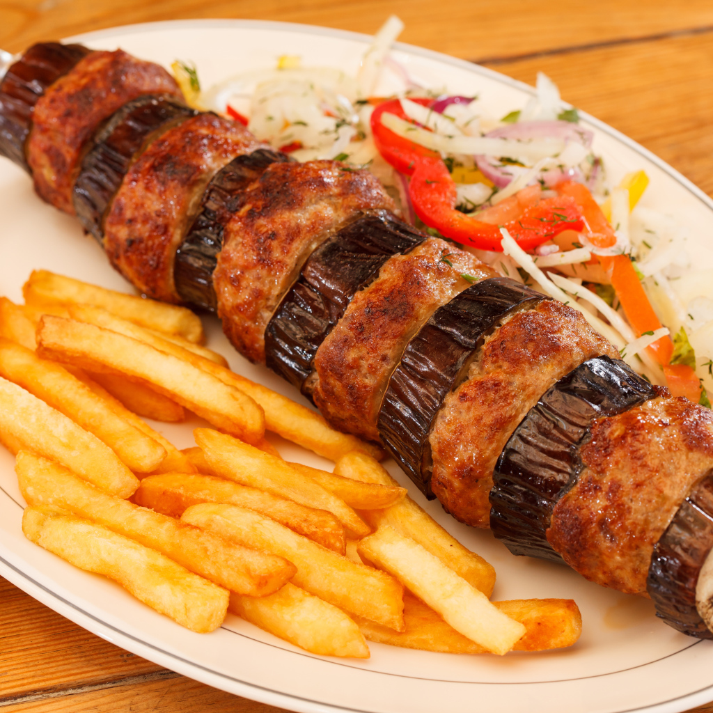 Шашлык с мясом и баклажанами на тарелке с картофелем фри 