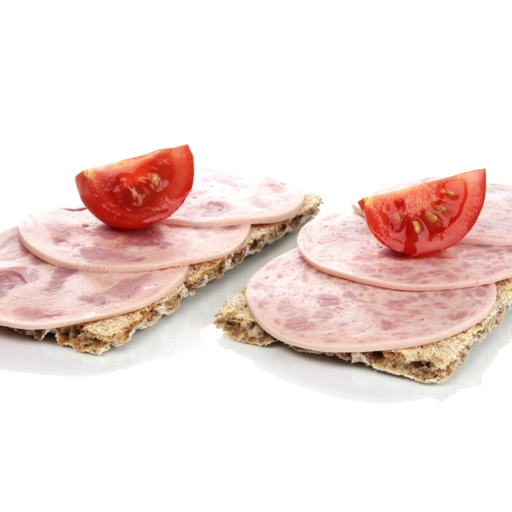 Тосты с колбасой и кусочками помидора на белом фоне