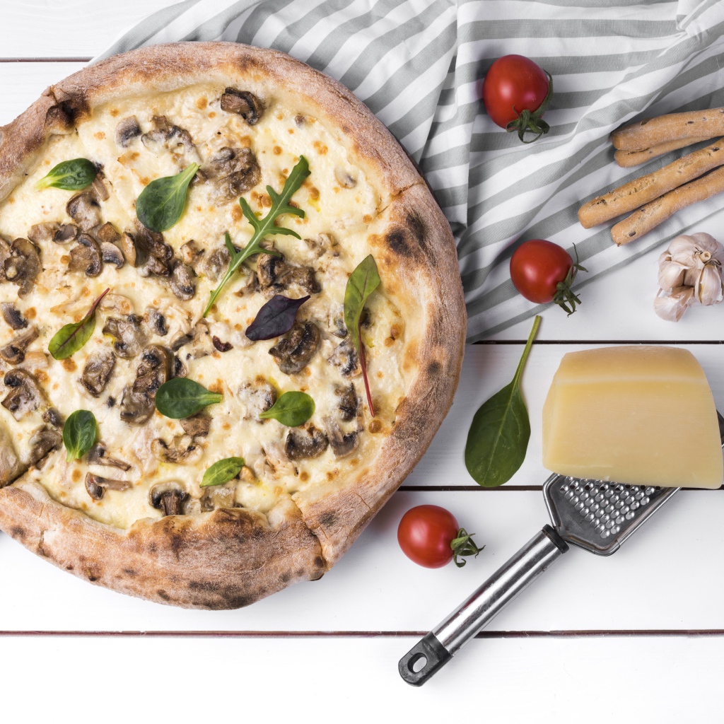 Пицца с грибами на столе с сыром и овощами