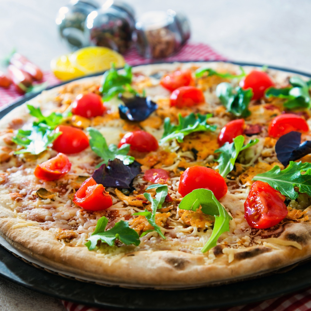 Пицца с помидорами, рукколой и сыром на столе