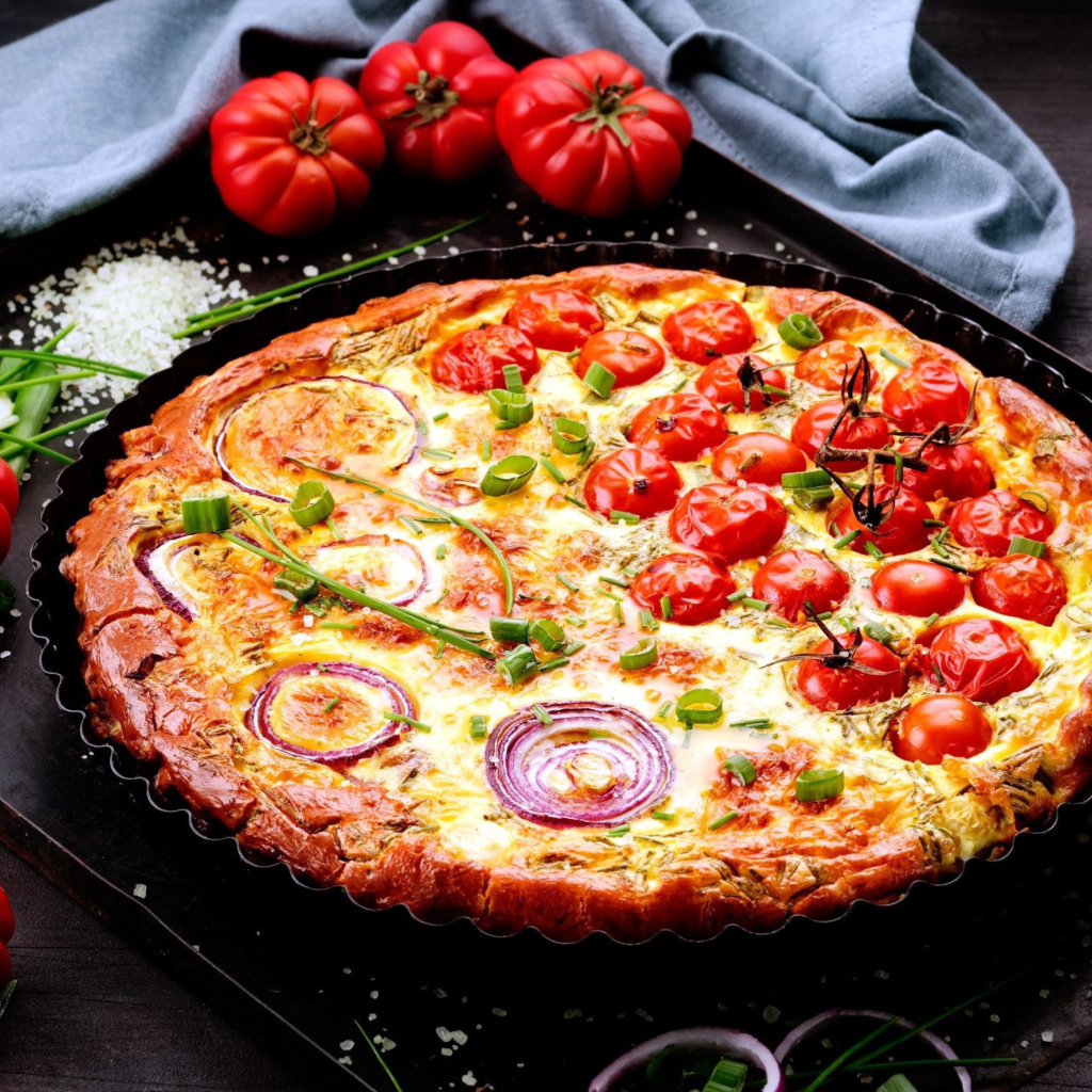 Пицца с помидорами и луком на подносе с овощами