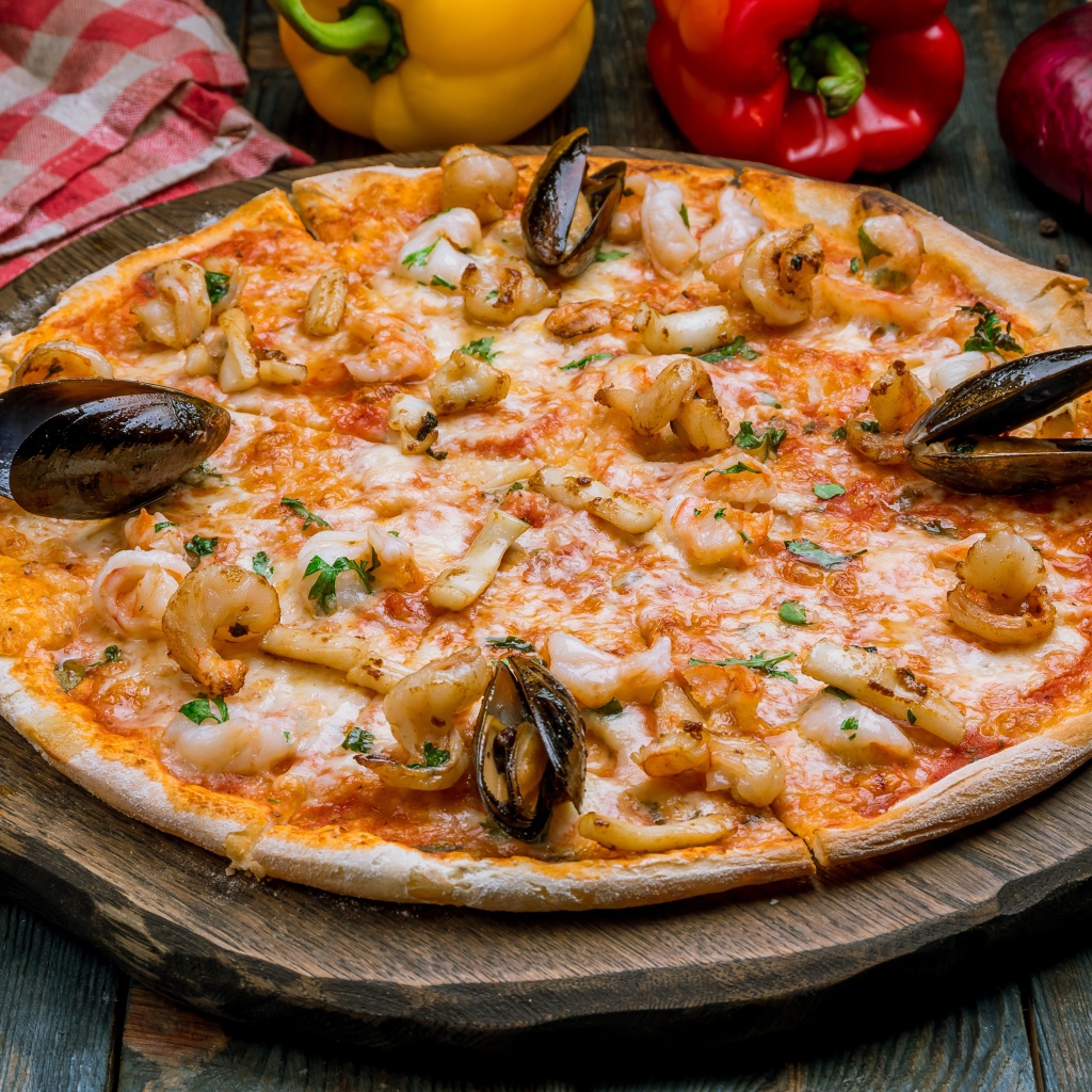 Вкусная пицца с морепродуктами на деревянной доске