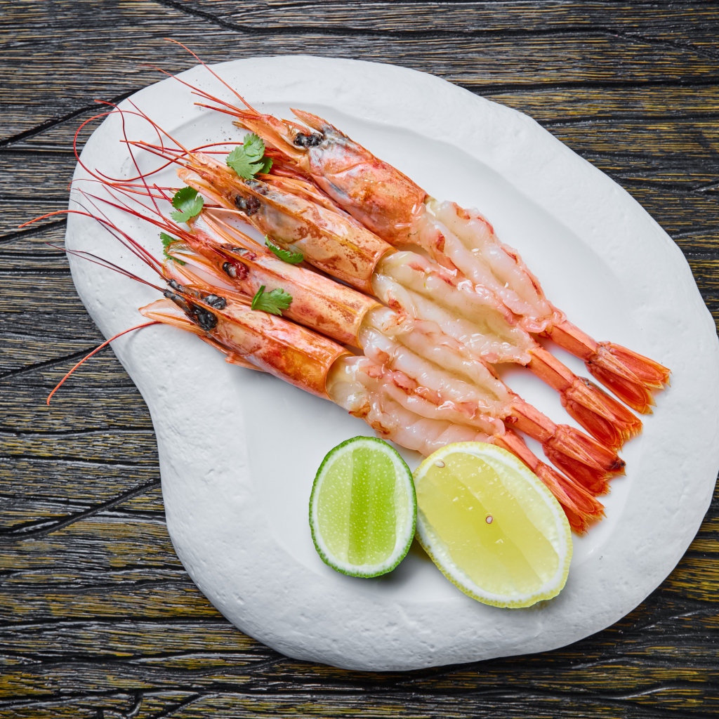 Аппетитные креветки на белой тарелке с лимоном