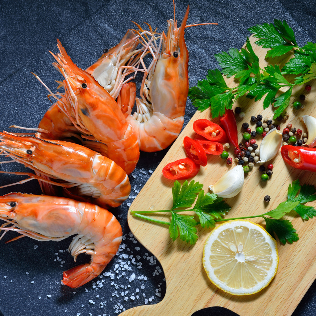 Вареные креветки на столе со специями и зеленью