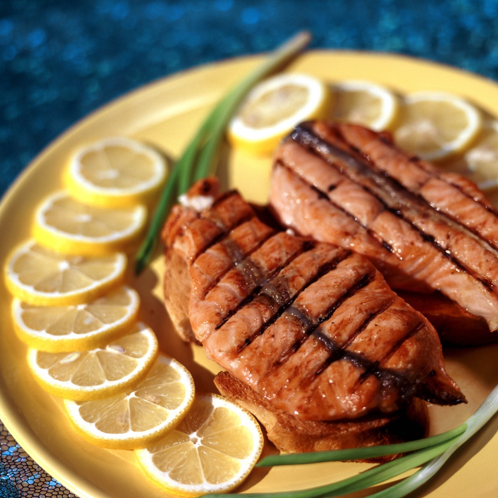 Grilled red fish with lemon slices and spring onions
