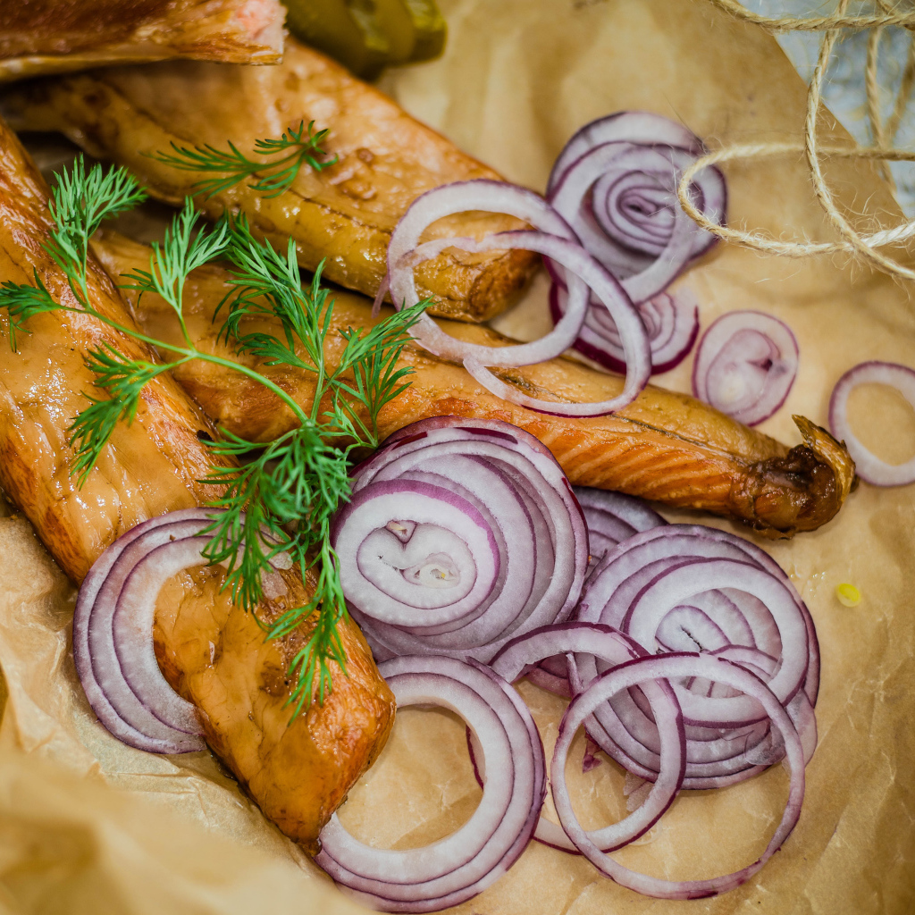 Копченое филе рыбы на бумаге с луком