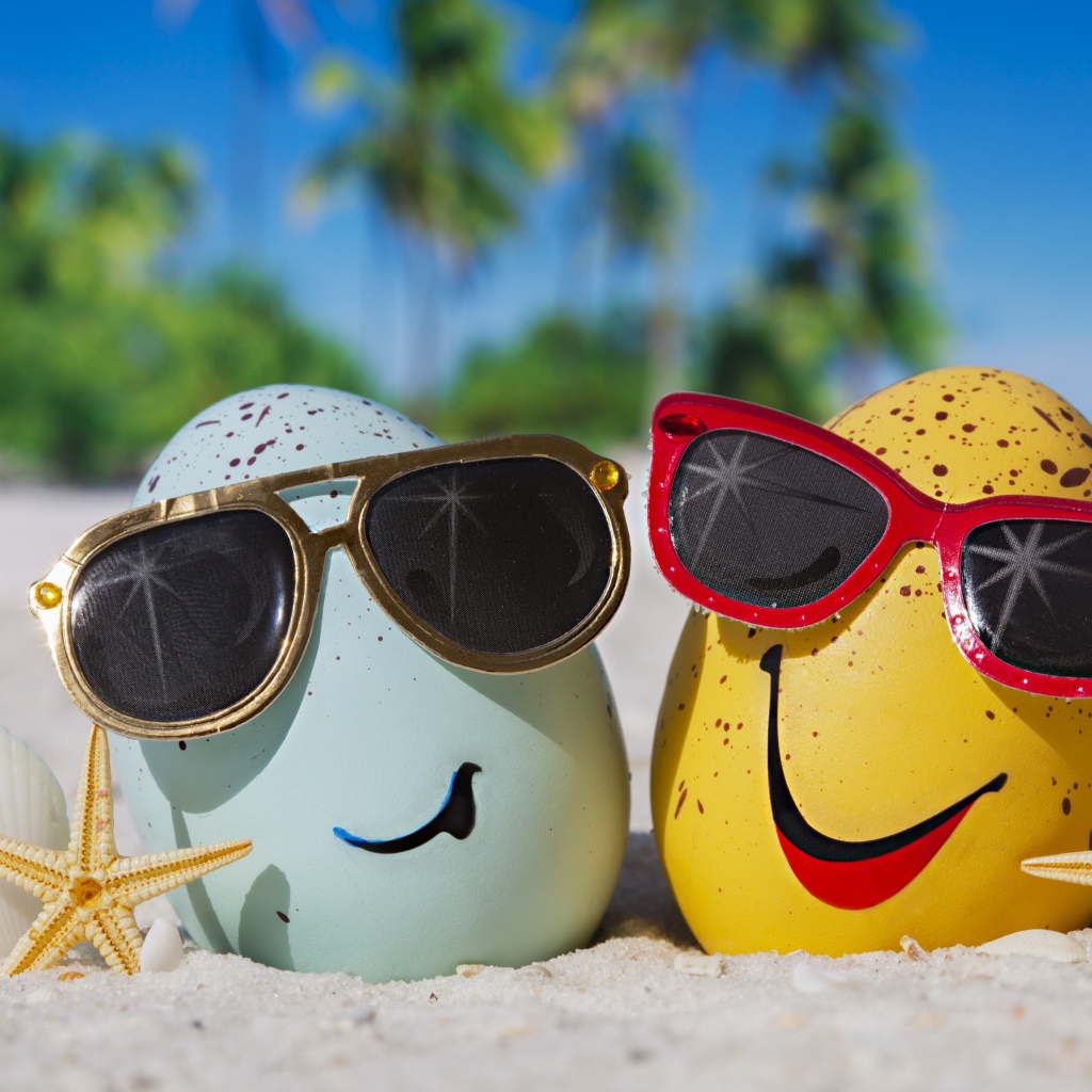 Два яйца в солнечных очках на морском песке летом