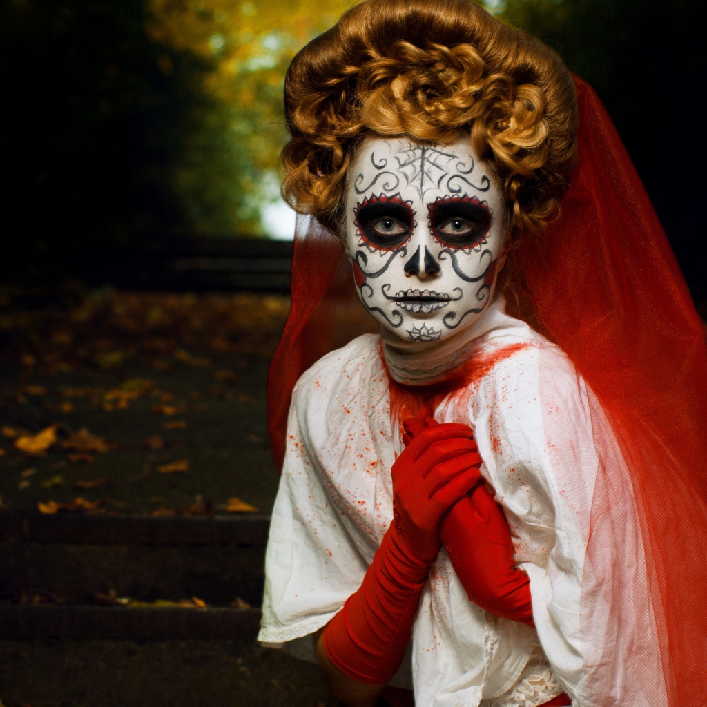 Девушка с маской на лице и красной фатой на праздник Хэллоуин 