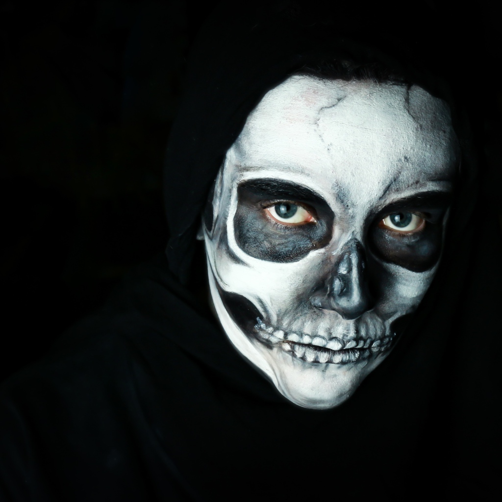 Girl with a mask with makeup on her face on a black background