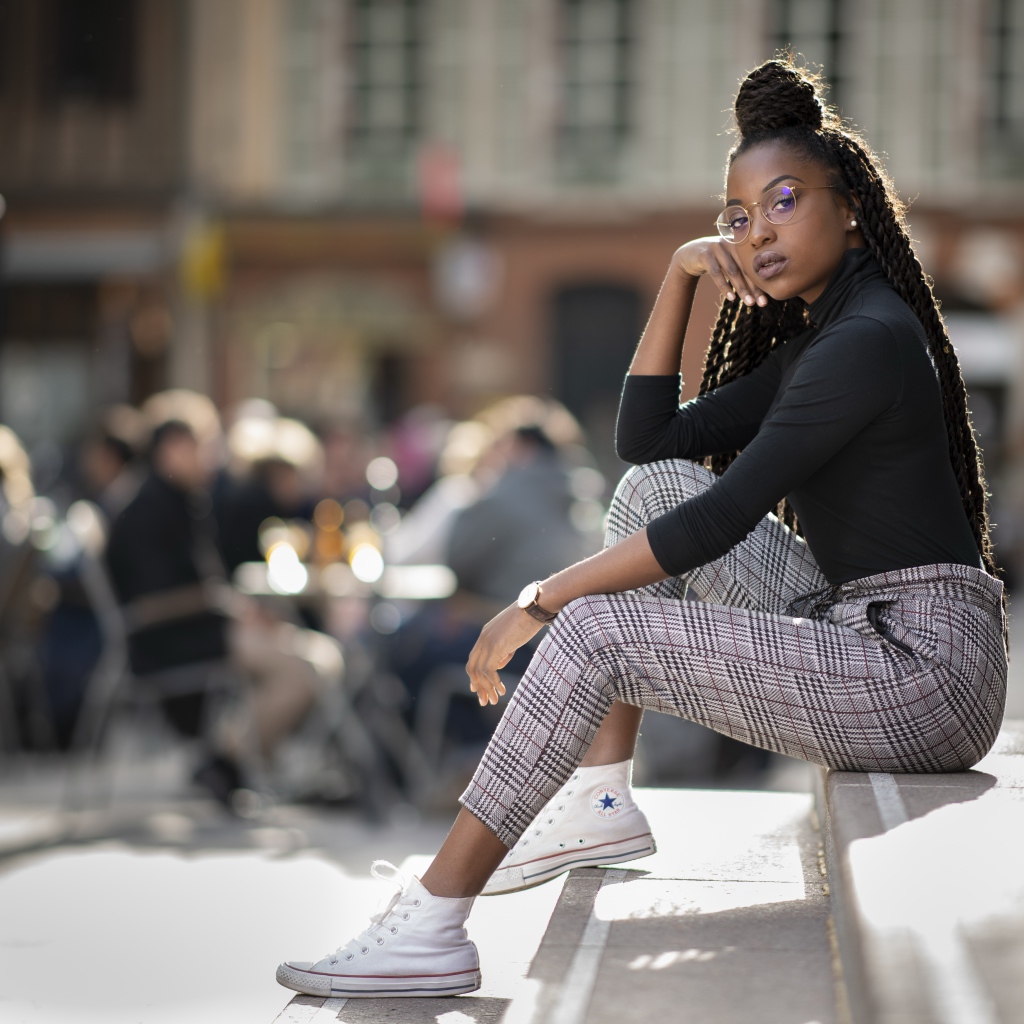 Красивая темнокожая девушка сидит на ступеньках