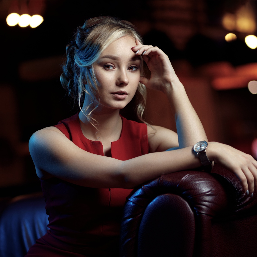 Красивая девушка с часами на руке сидит в кресле