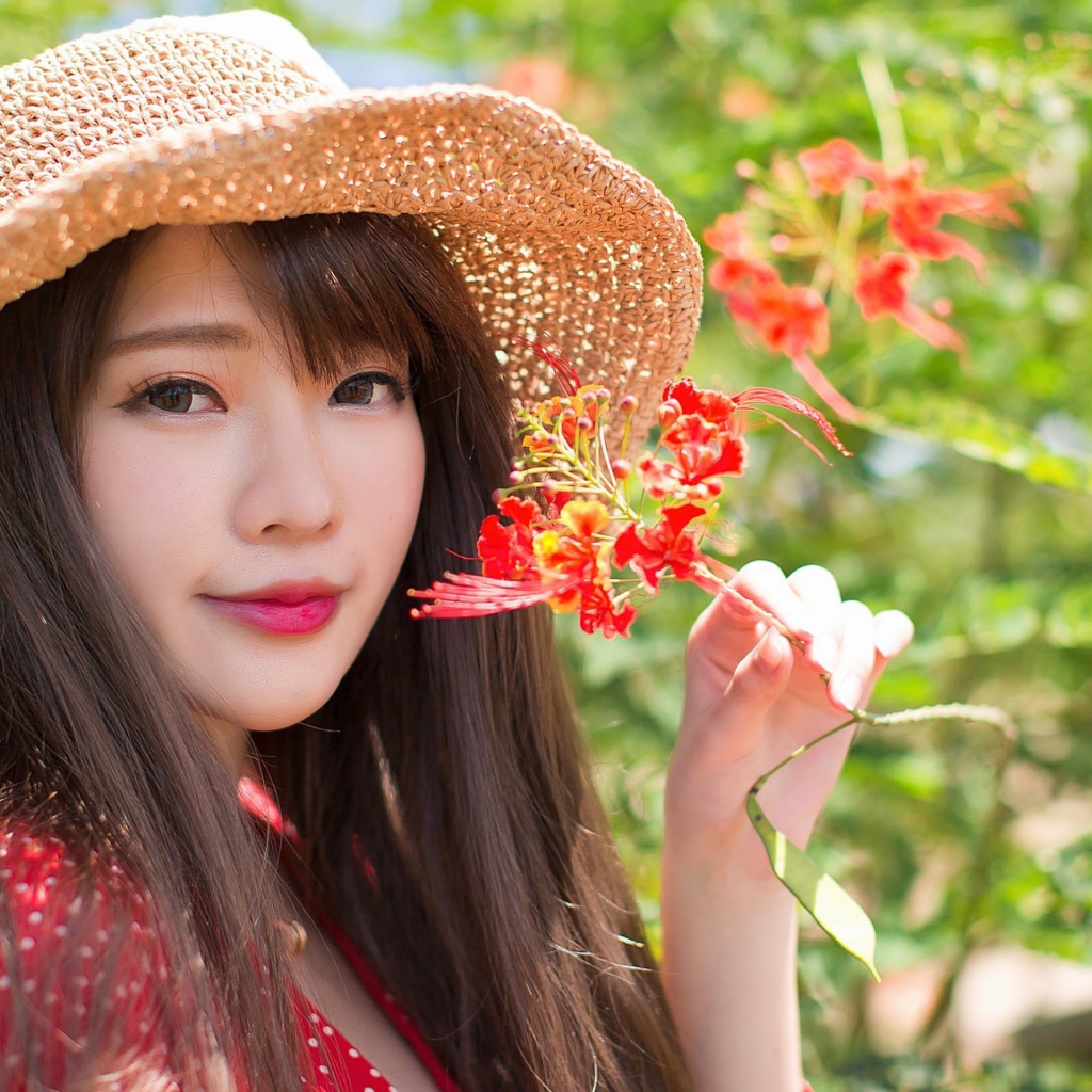 Девушка азиатка в шляпе с красным цветком