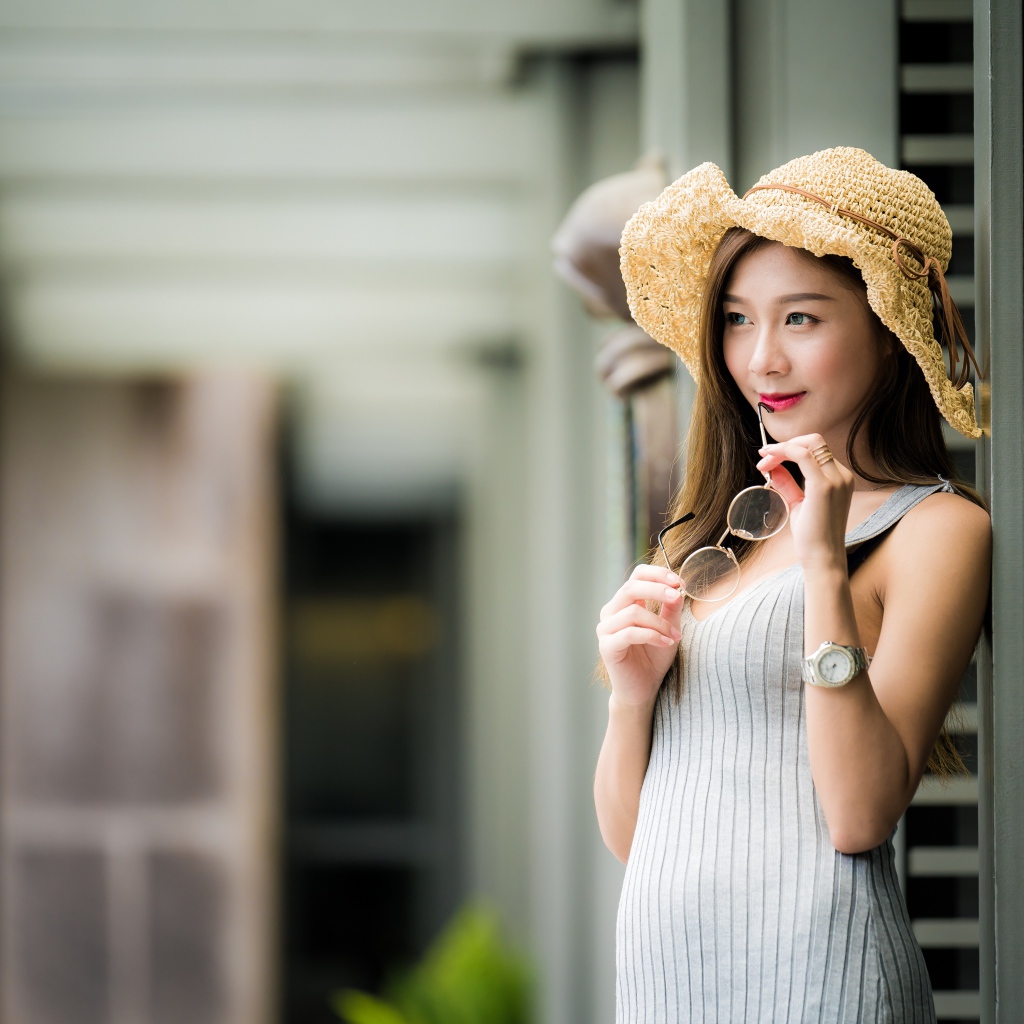 Девушка азиатка в шляпке с очками в руках 