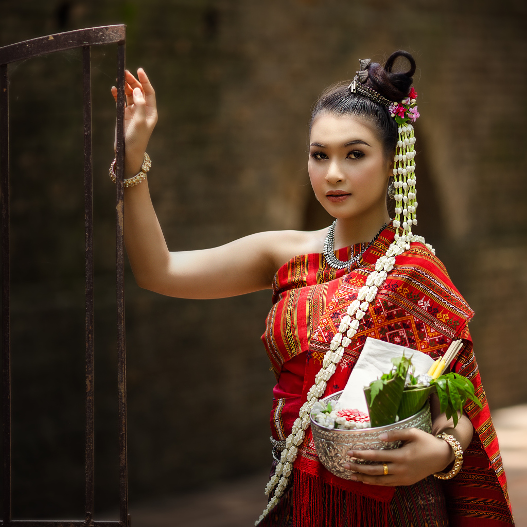 Девушка азиатка в костюме стоит у железных ворот