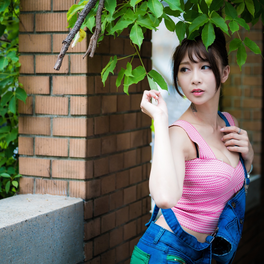 Молодая девушка азиатка у стены с зелеными листьями