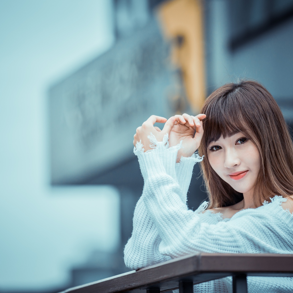 Молодая девушка азиатка в белом свитере на балконе