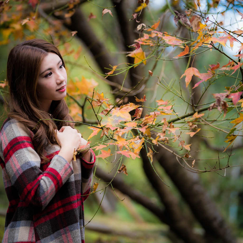 Красивая азиатка стоит у дерева