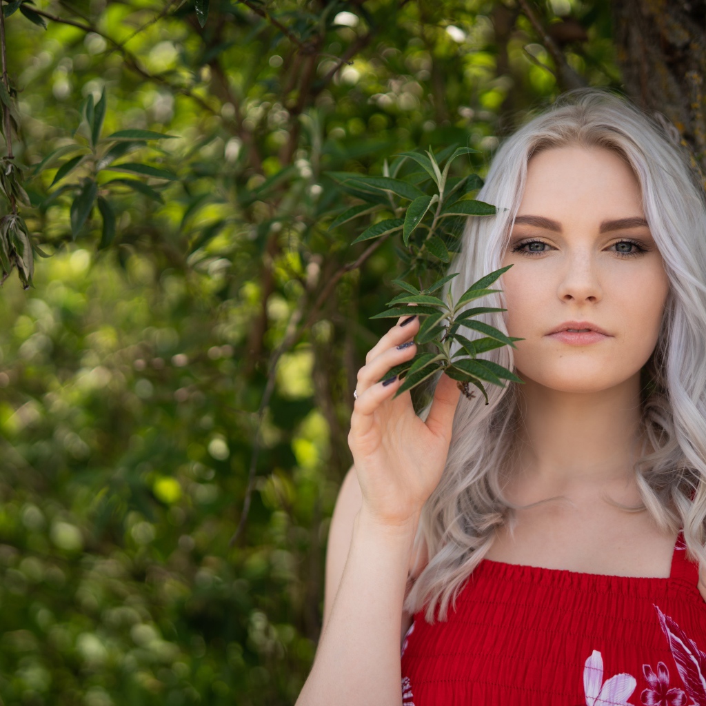 Красивая блондинка стоит у дерева 