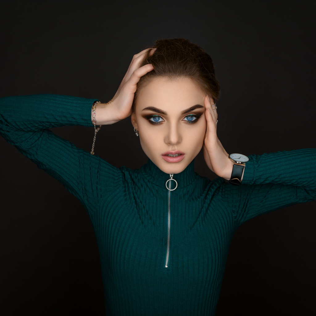 Красивая голубоглазая девушка в зеленом свитере на черном фоне