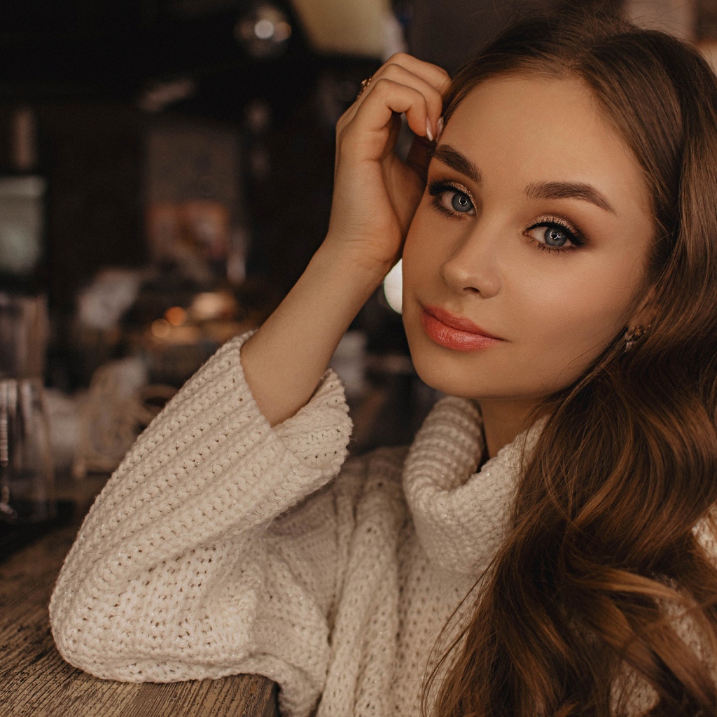 Красивая голубоглазая девушка в белом свитере в кафе