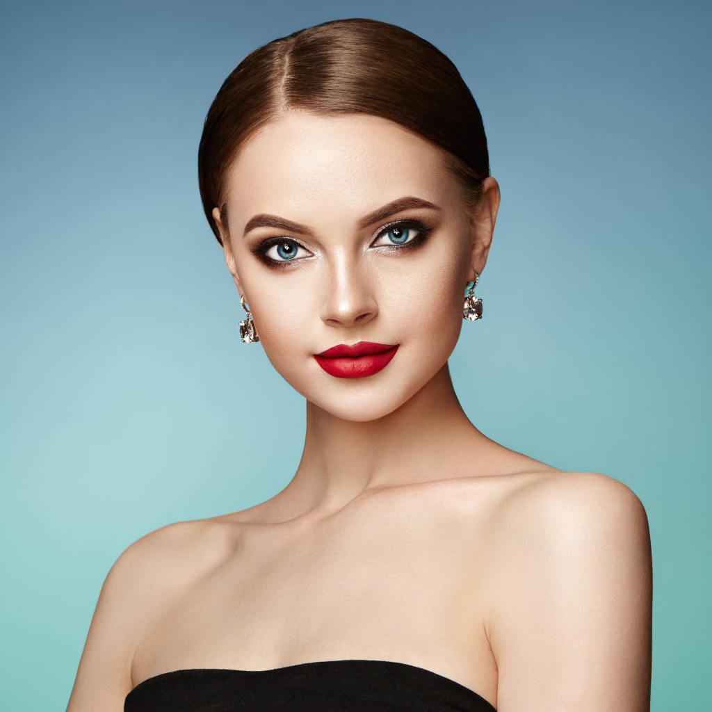 Красивая голубоглазая девушка с накрашенными губами и серьгами в ушах