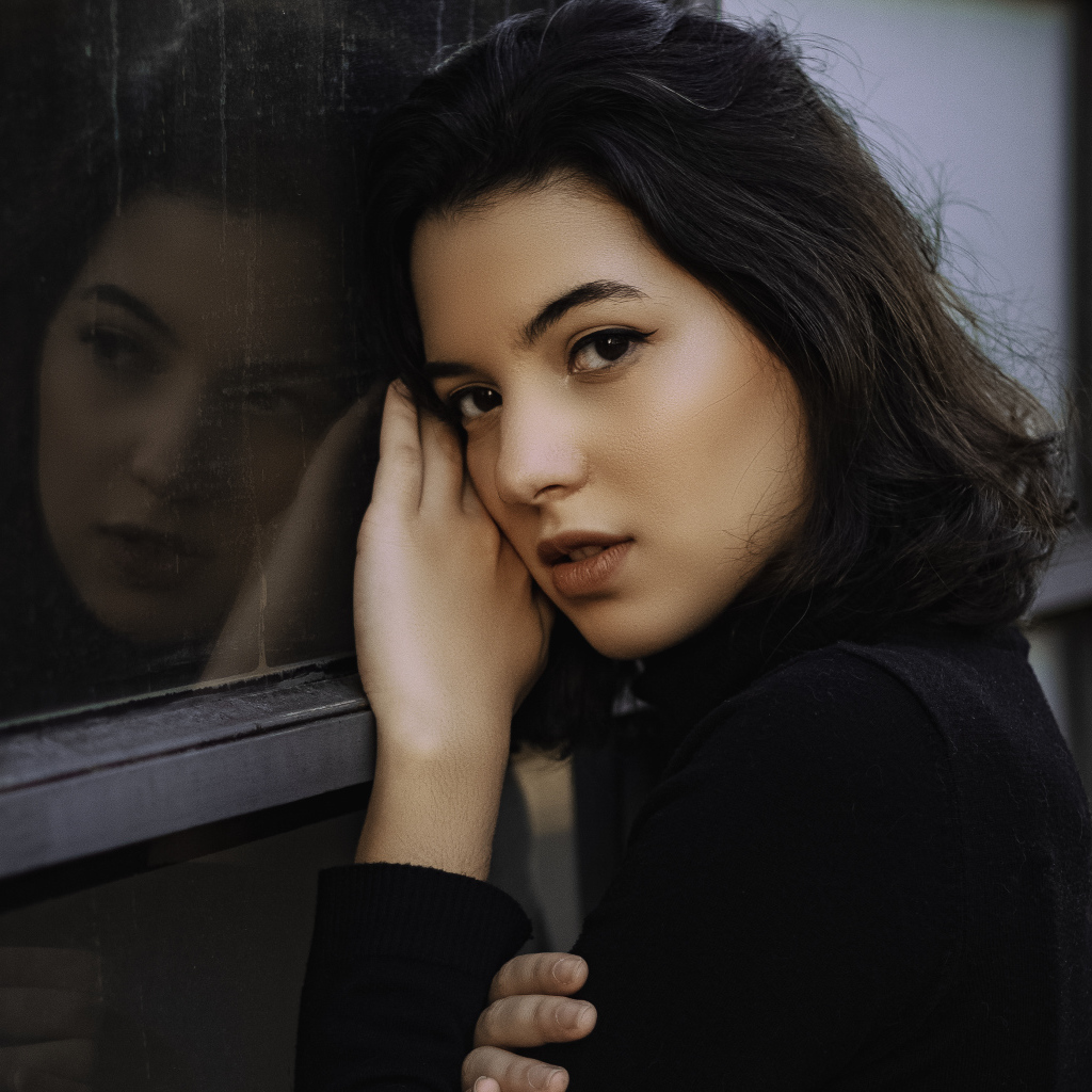 Красивая кареглазая девушка стоит у окна