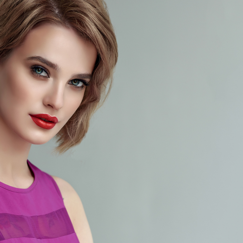 Красивая девушка шатенка с короткой стрижкой на сером фоне