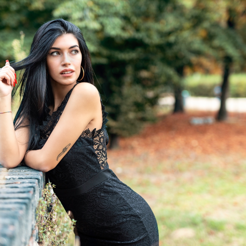 Красивая брюнетка в черном платье в парке