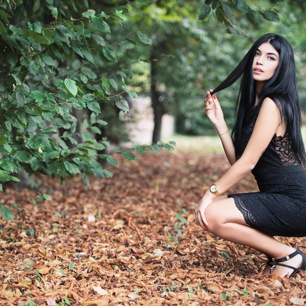 Красивая брюнетка в черном платье в парке осенью 