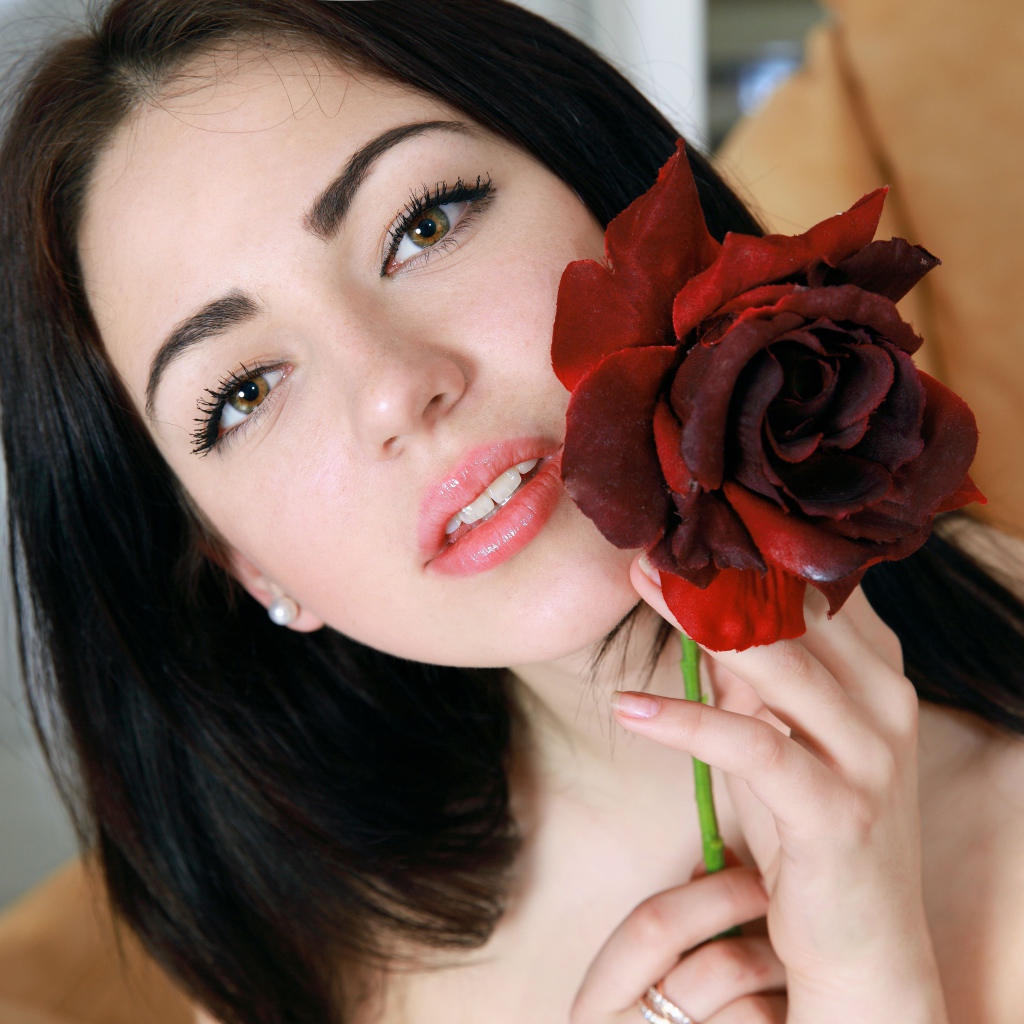 Красивая брюнетка с розой в руке крупным планом