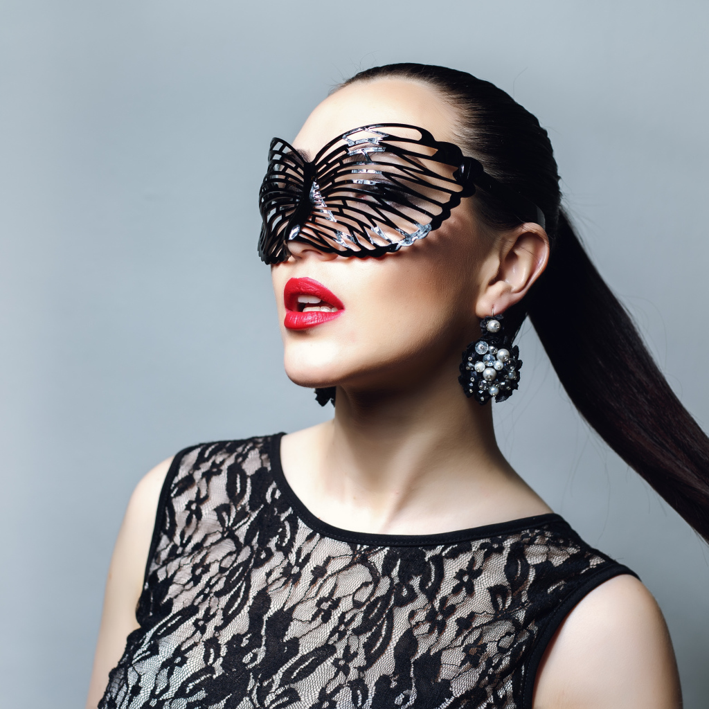 Красивая модная девушка в черной маске на сером фоне