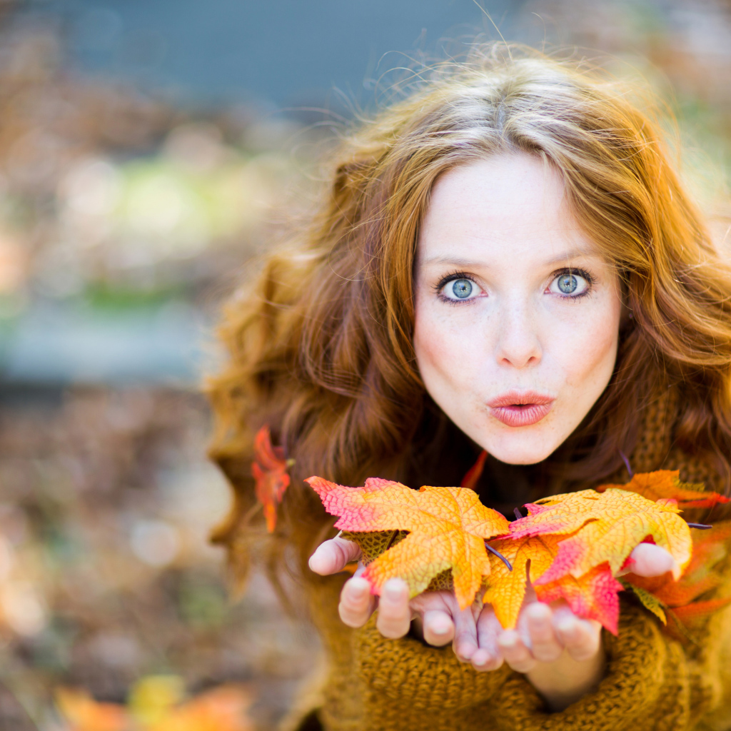 Красивая девушка сдувает листья с ладоней