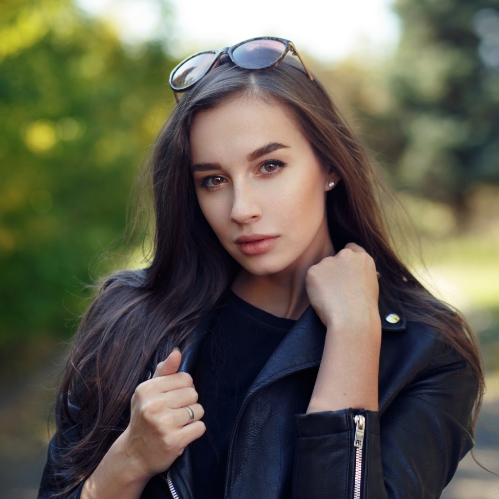 Красивая девушка в черной куртке с очками на голове