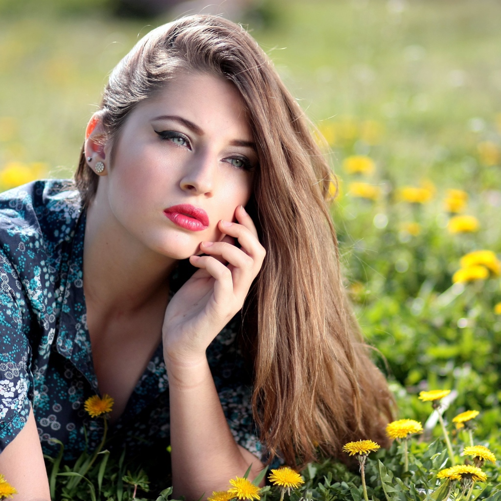 Красивая девушка в платье лежит на траве с одуванчиками