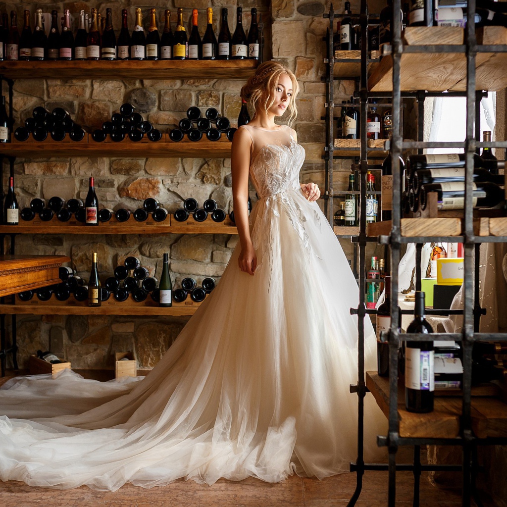 Красивая девушка в пышном свадебном платье в винном погребе