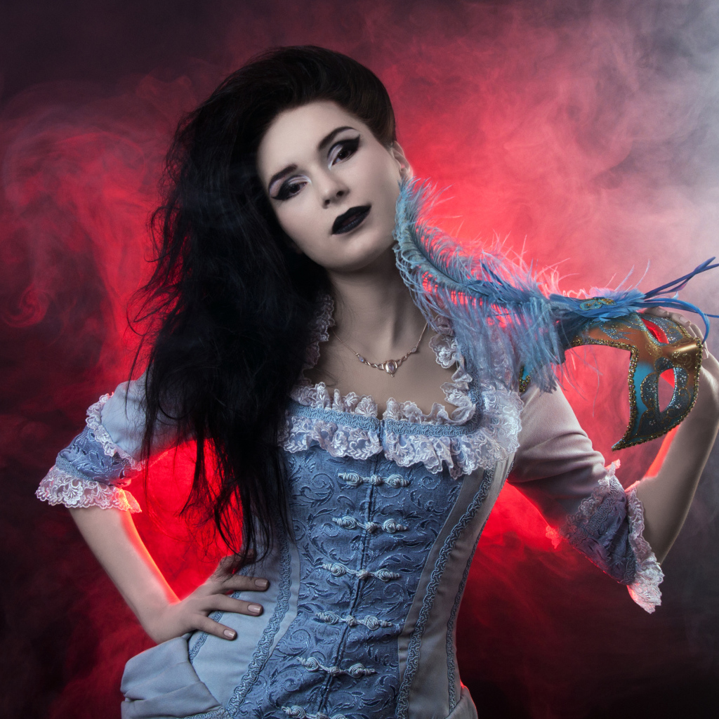Красивая девушка в старинном платье с маской в руке