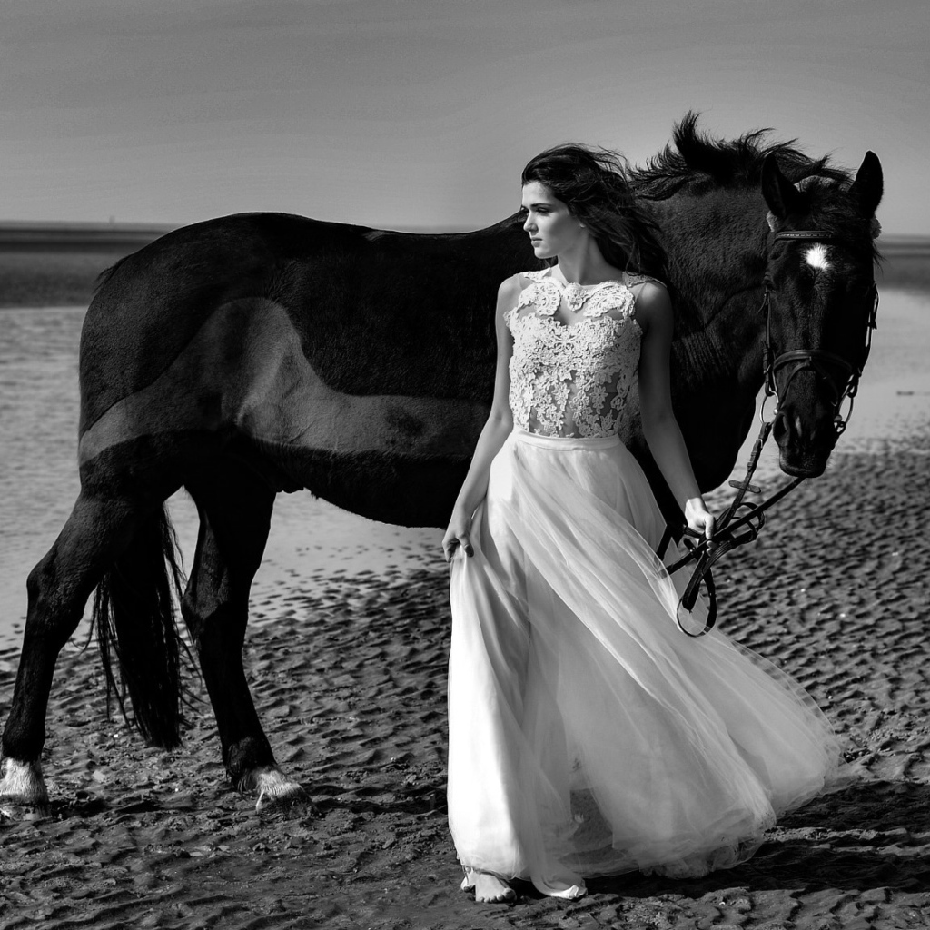 Красивая девушка в свадебном платье с лошадью на берегу моря