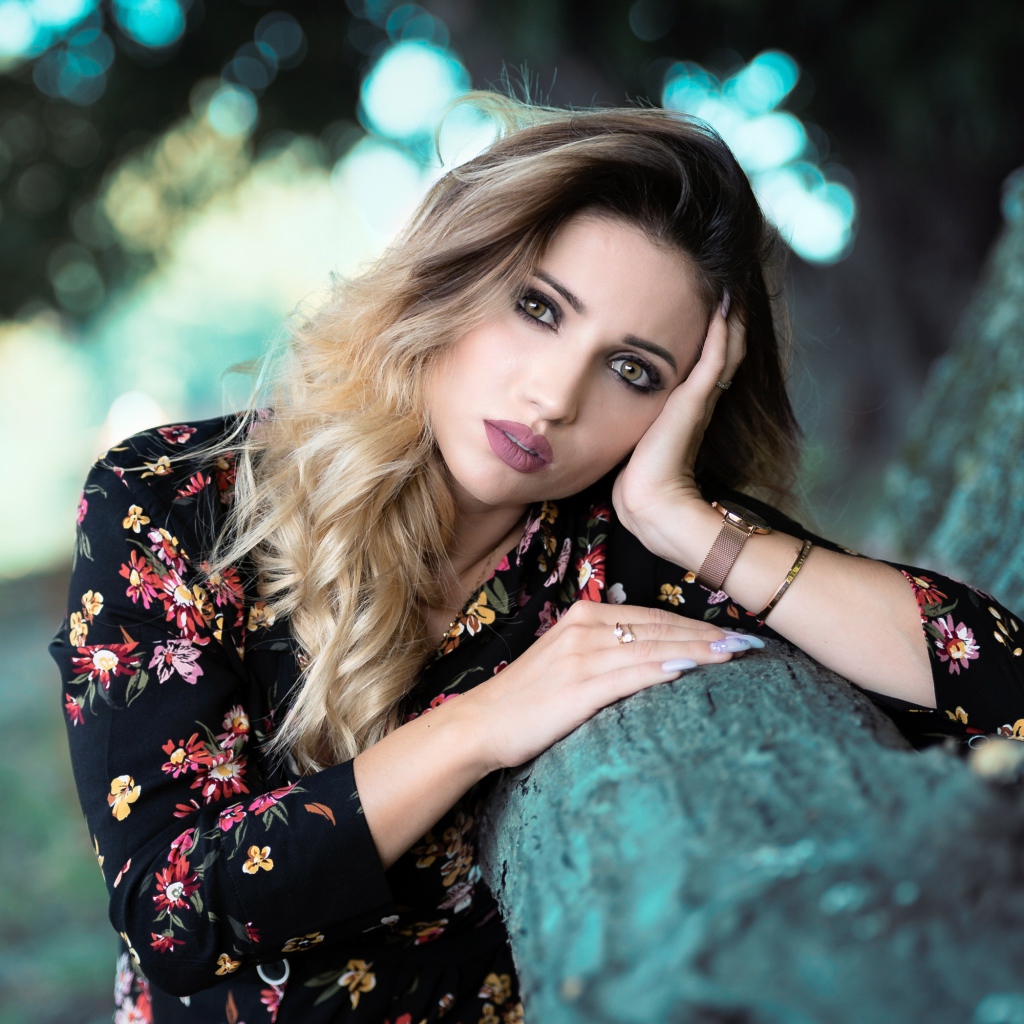 Красивая девушка в цветастом платье у дерева