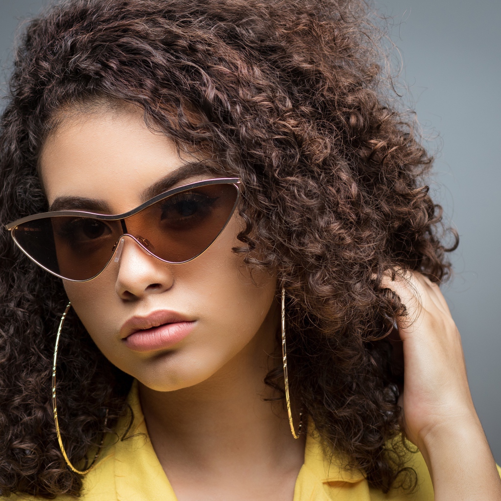 Красивая девушка в солнечных очках на сером фоне