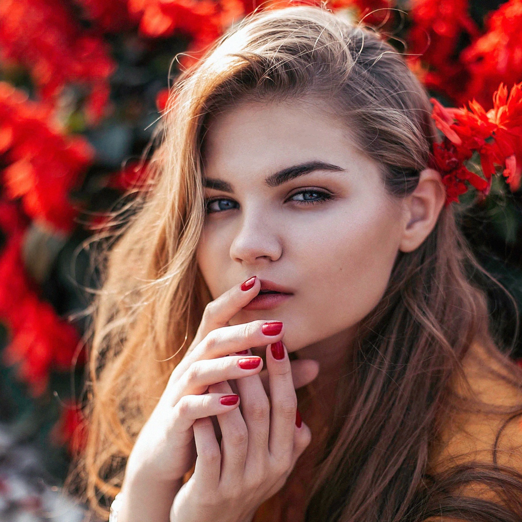Красивая девушка на фоне красных цветов
