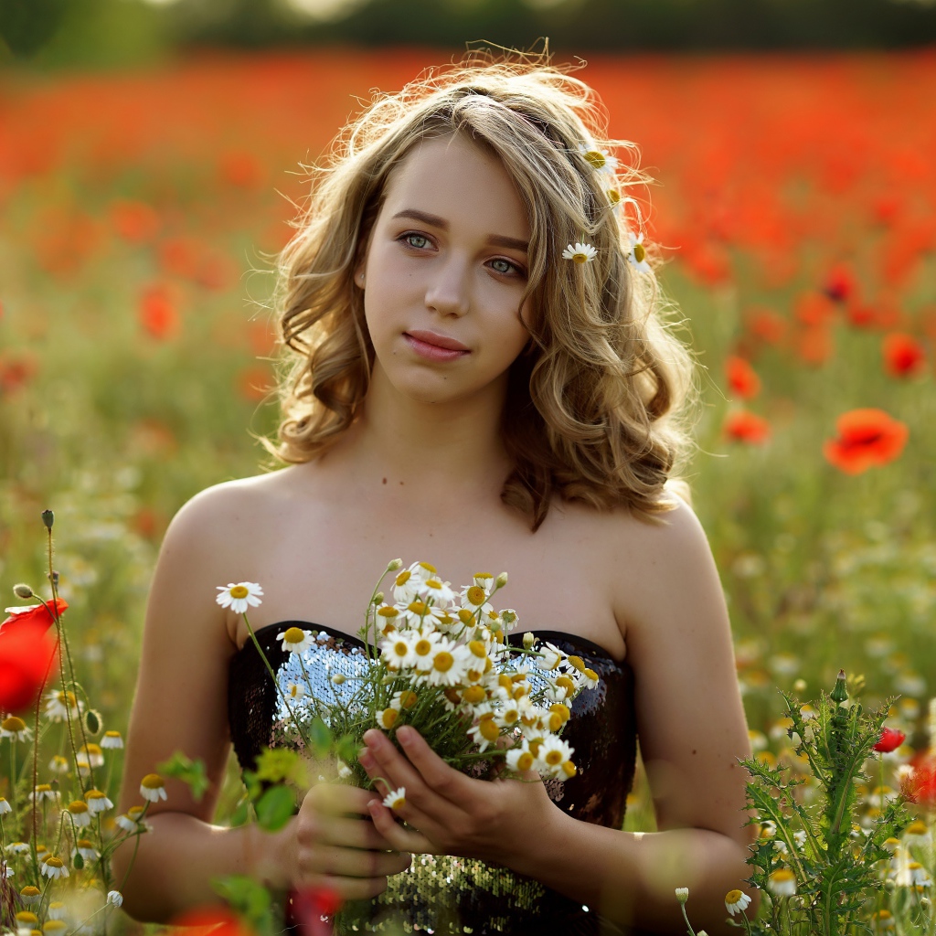 Красивая девушка с букетом ромашек на поле с маками