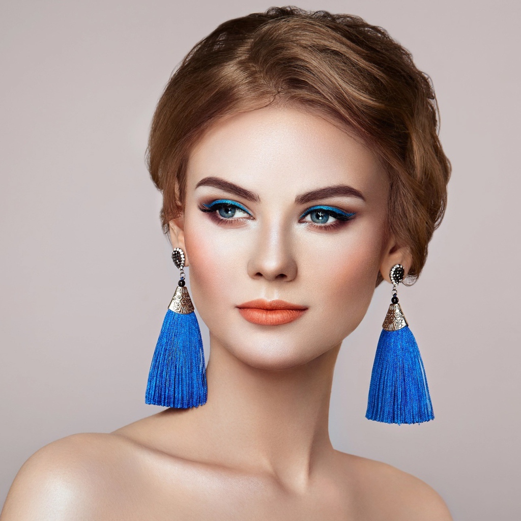 Красивая девушка с синими сережками на сером фоне