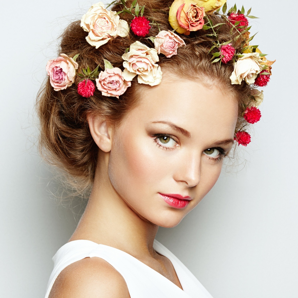 Красивая девушка с цветами в волосах на сером фоне