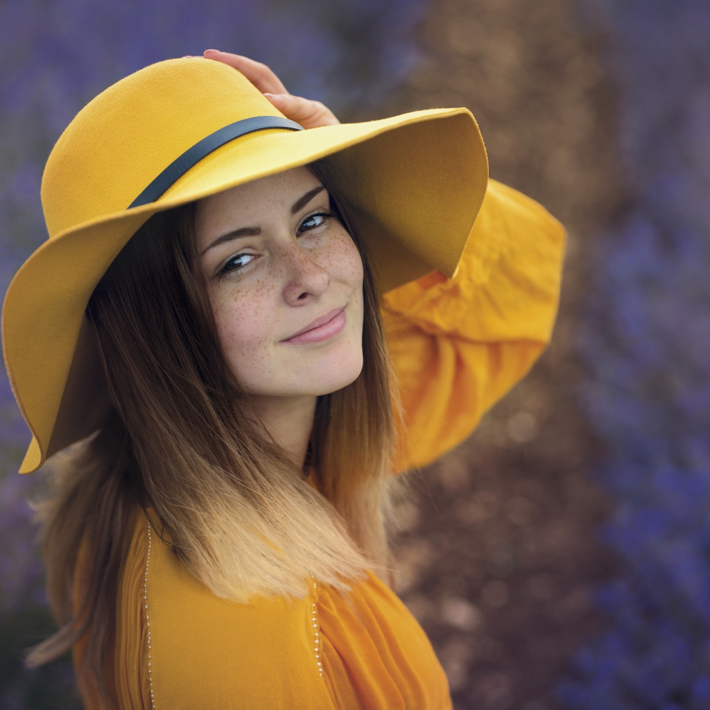 Красивая девушка с веснушками на лице в желтой шляпе