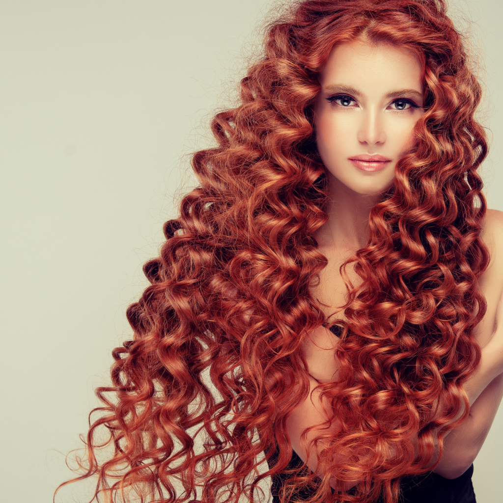 Красивая девушка с длинными рыжими волосами на сером фоне