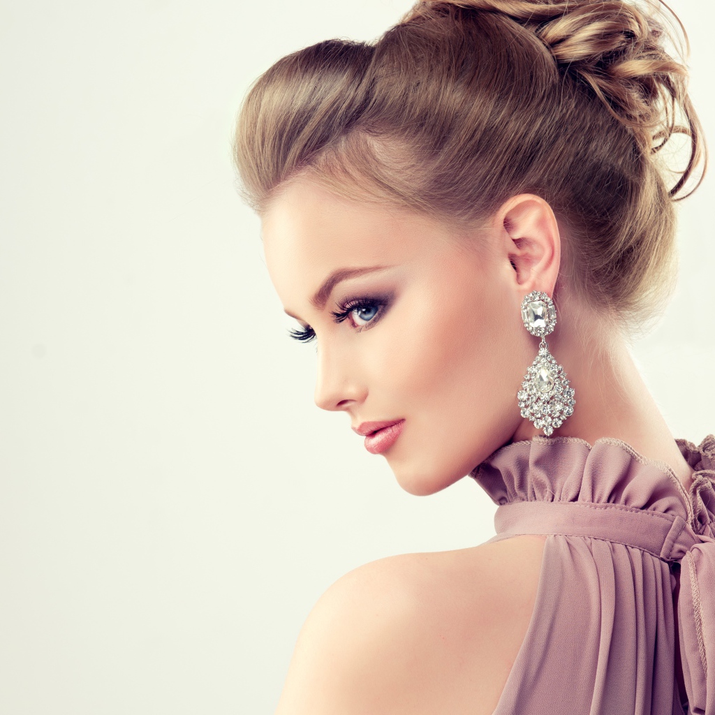 Красивая девушка с макияжем и прической на сером фоне