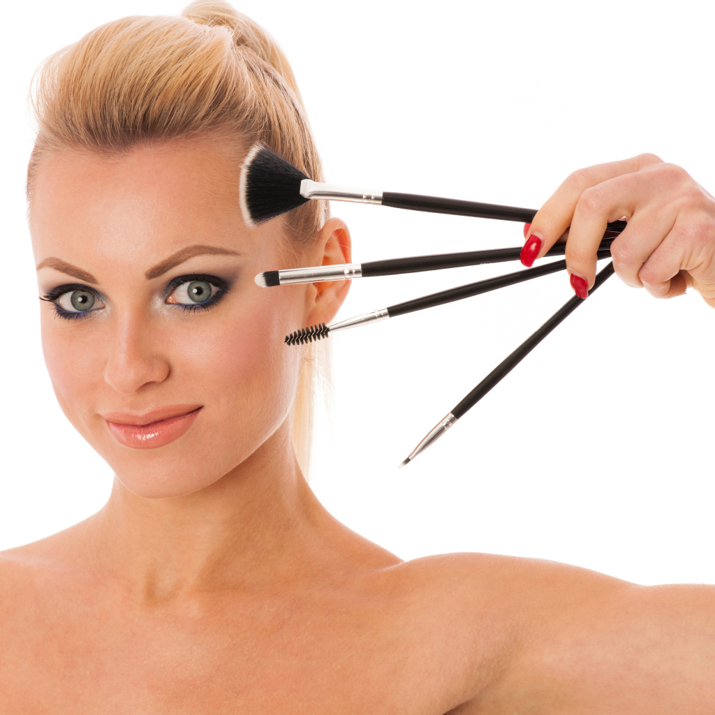 Красивая девушка с кистями для макияжа на белом фоне