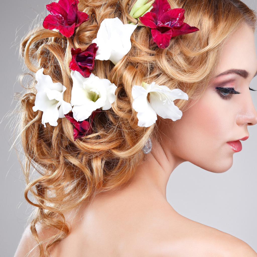 Красивая девушка с цветами петунии в волосах на сером фоне