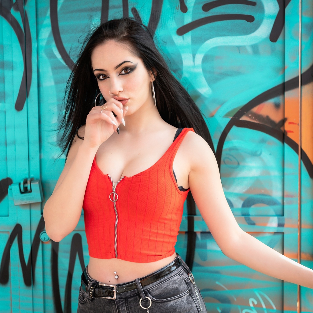 Красивая девушка с пирсингом стоит у стены