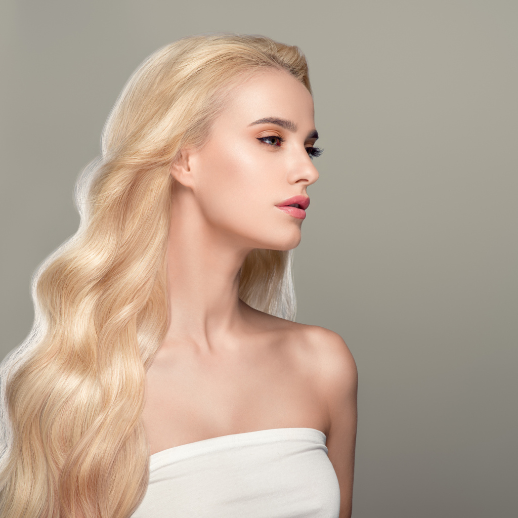 Красивая длинноволосая девушка блондинка на сером фоне